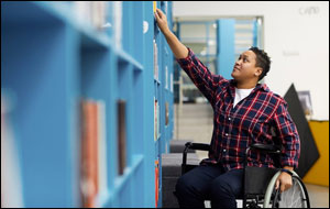 African American student in wheelchair reaches for a book on a high shelf. Credit: Shutterstock 1537798346