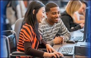 Asian female college student and African American male college student work together at a desktop computer. Credit: iStockphoto
